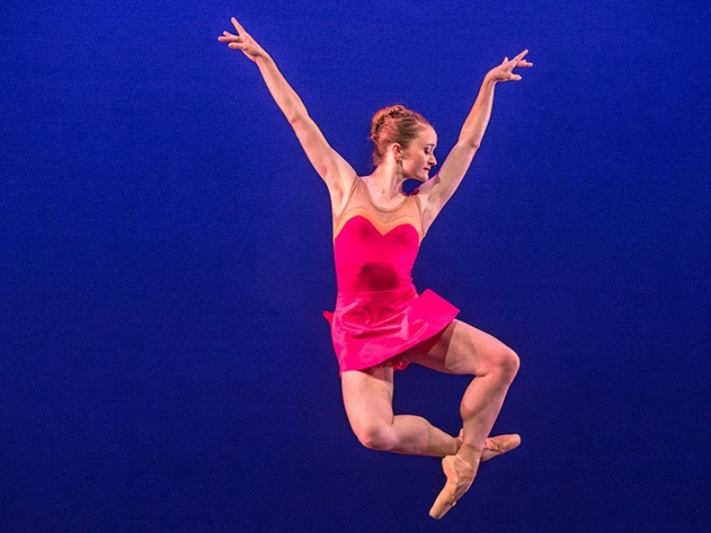 Maggie jumping through the air in pink skirt.