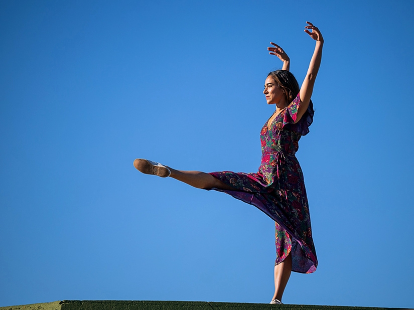 Tess dancing outside with blue sky in the background.