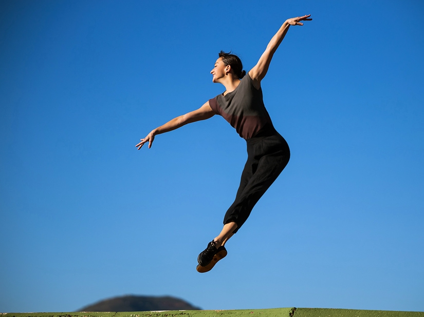 Terez jumping through the air with blue sky in the background.