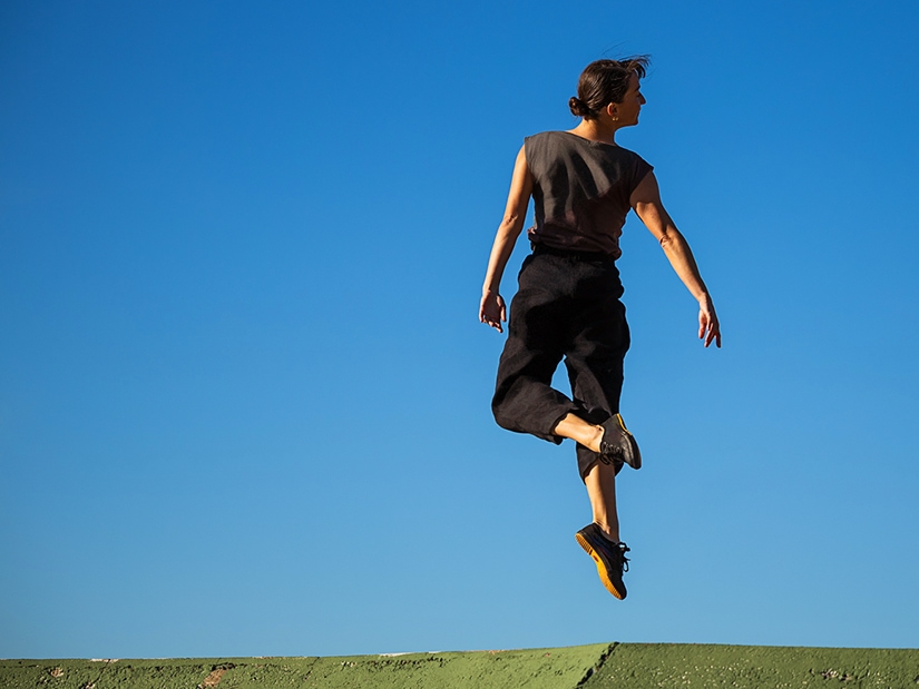 Terez jumping with blue sky in the background.