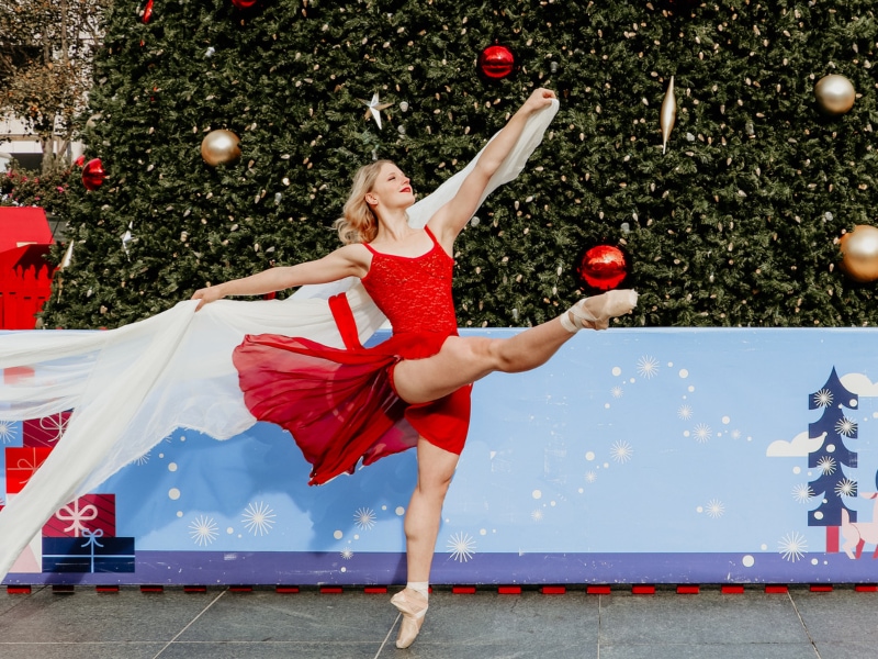 Tessa dancing in front of a Christmas tree in a red dress. Photo by Brennan Wall