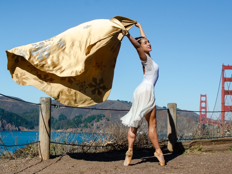 Tess dancing on pointe with gold cape blowing in the wind.